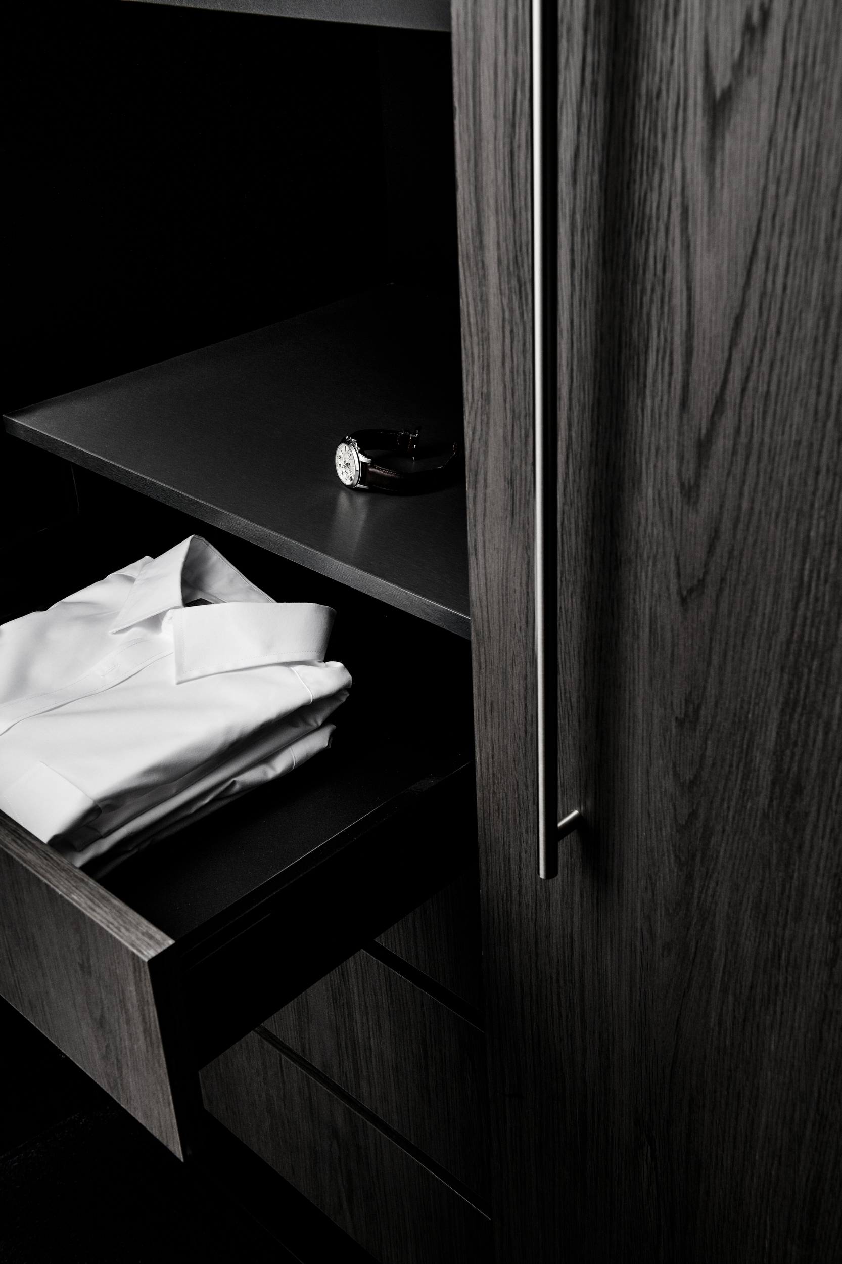 A closet with custom joinery crafted from Cellupal stunningly accurate timber-look laminate in Sparka, a grey decor with 3D woodgrain feature and a super matt finish. A folded white shirt is pictured in an open drawer.