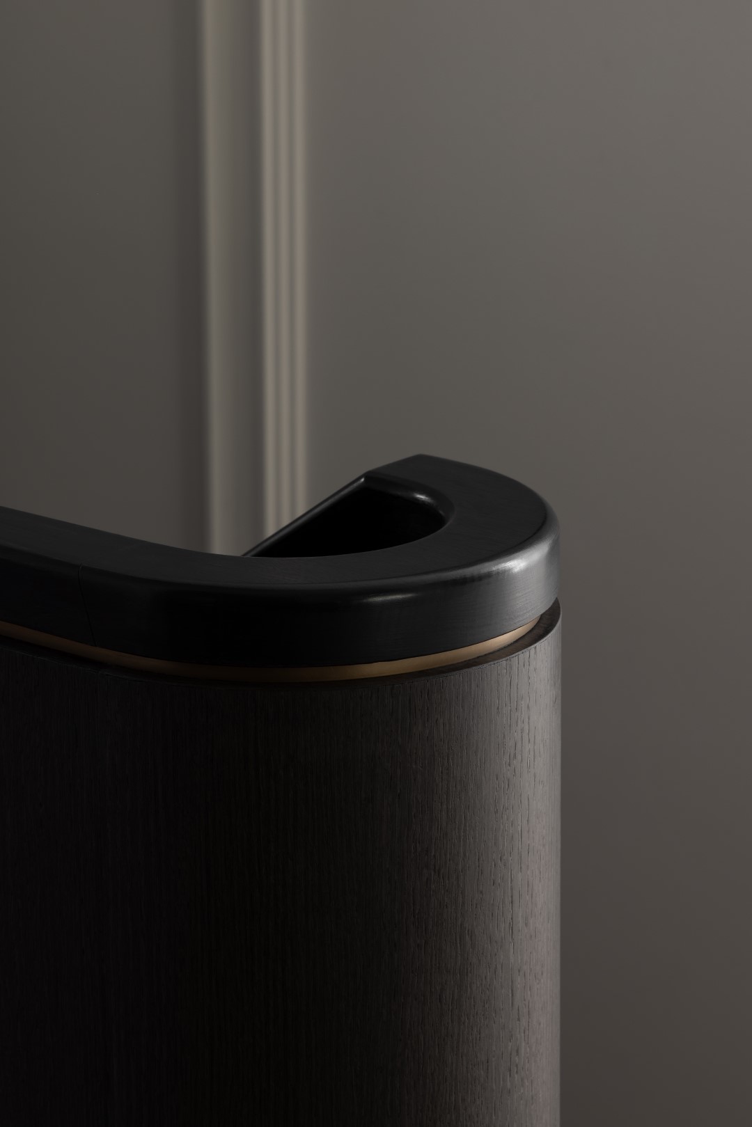 Detailed shot of the handrail of a custom staircase, showcasing Lignapal prefinished timber veneer in 151.07 Cinder Gum. The dark timber veneer is complemented by subtle bronze accents, creating a sophisticated and elegant aesthetic.