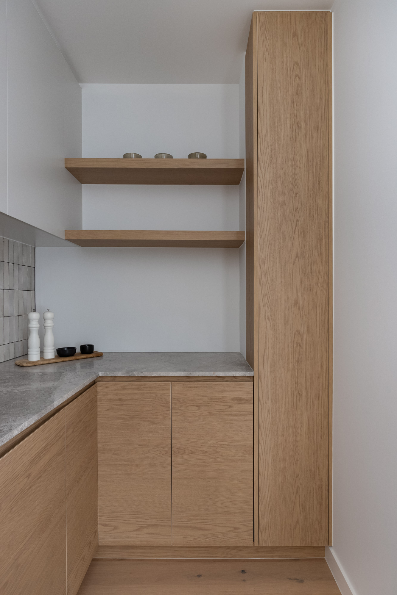 A modern kitchen featuring Cellupal Eik timber-look laminate joinery with open shelving and a sleek gray stone countertop.