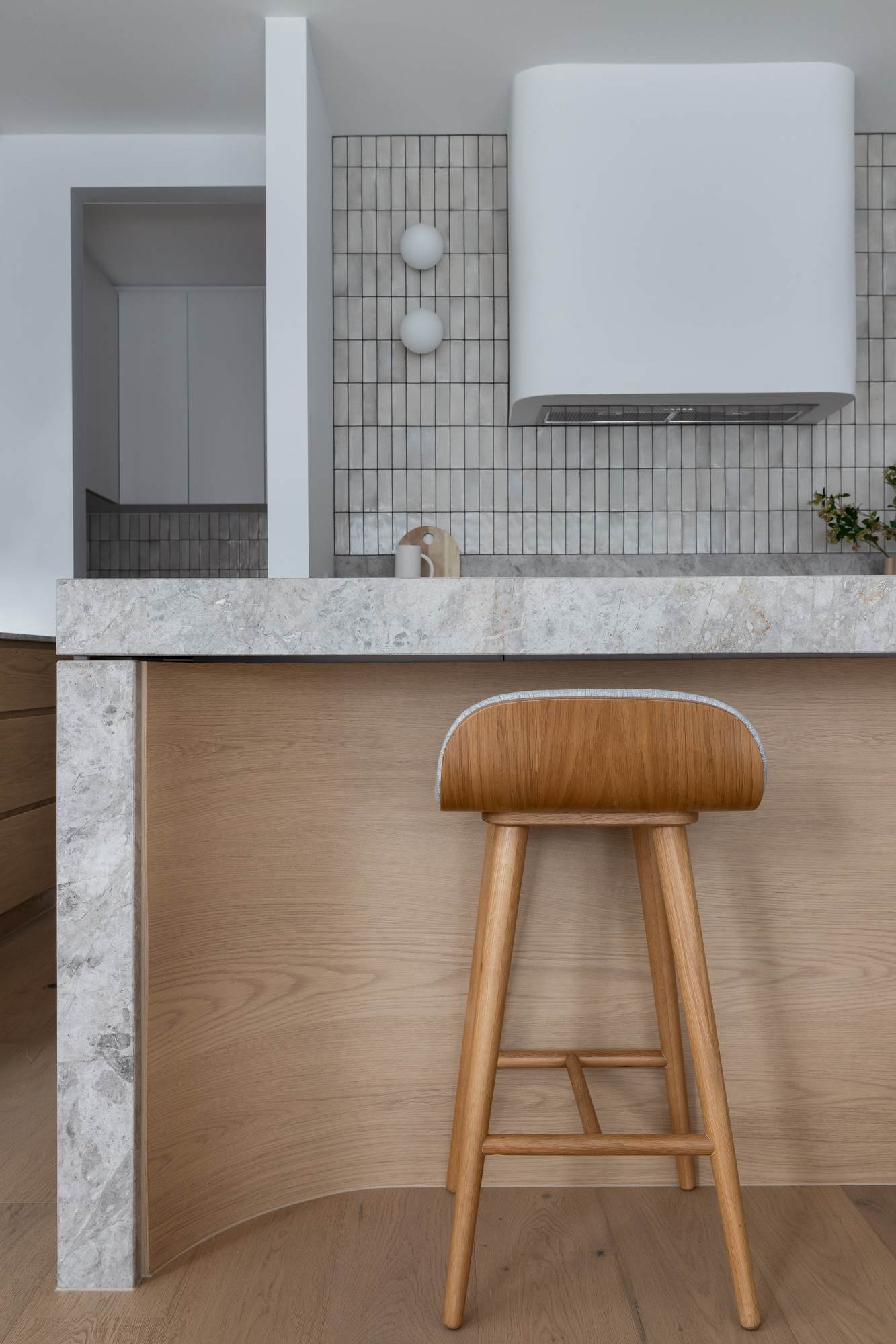 A modern kitchen featuring a curved application of Cellupal Eik oak-look laminate beneath the grey stone-topped island bench.