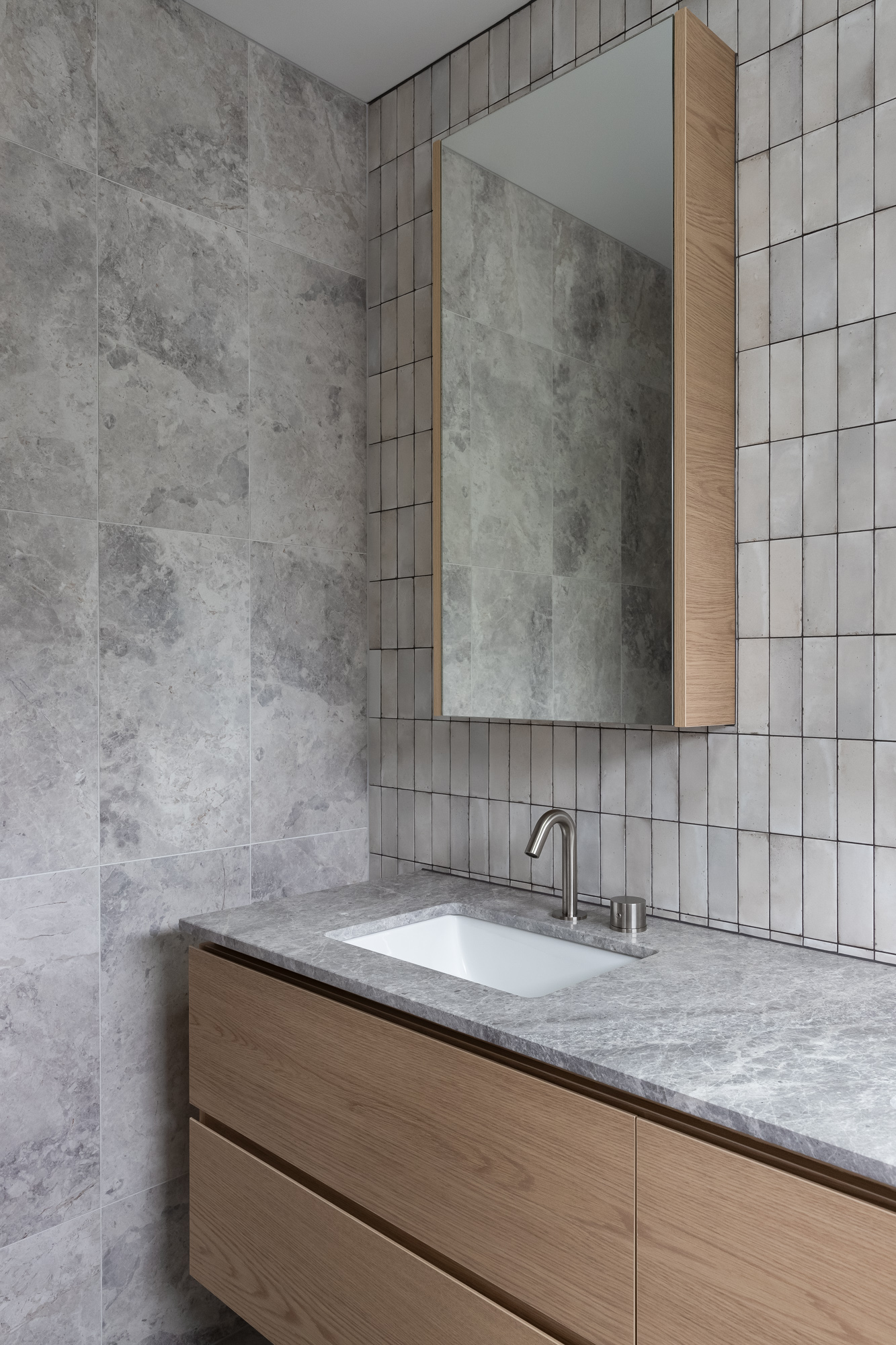 Sleek cabinetry crafted from Cellupal Eik oak-look laminate, plus a mirrored cabinet and grey stone countertop. The design is complemented by a modern tiled splashback and integrated sink.