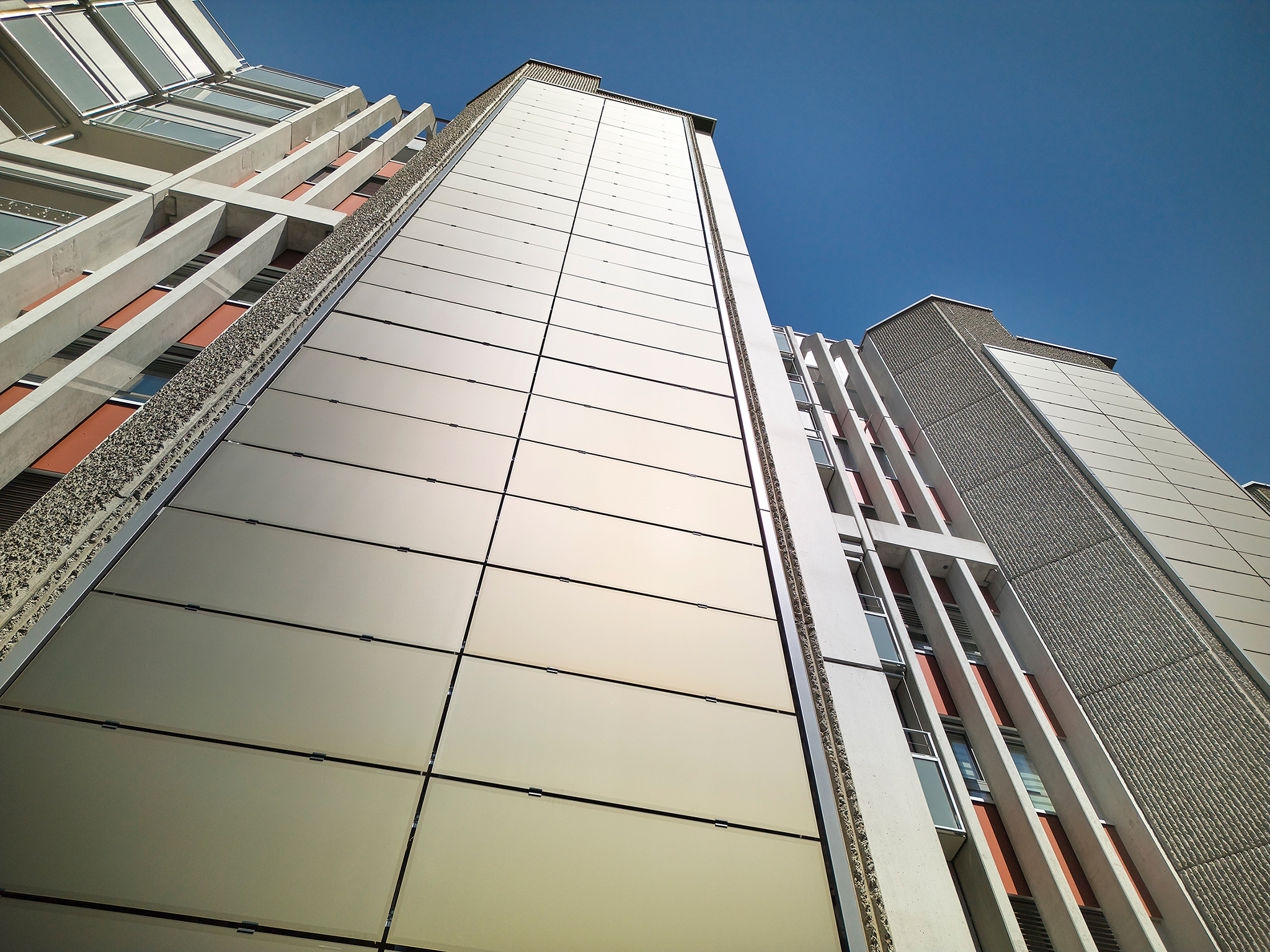 A close-up view of the Holenackerstraße residential tower in Bern, showcasing the SKALA BIPV Bronze 3001 retrofit solar facade seamlessly integrated into the high-rise exterior